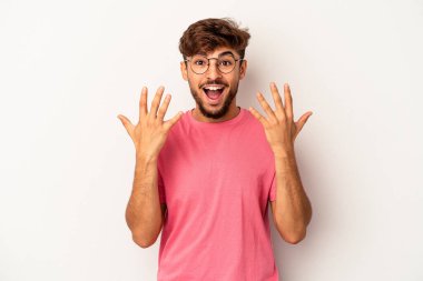 Genç melez adam gri arka planda izole edilmiş. Elleriyle on numarayı gösteriyor..