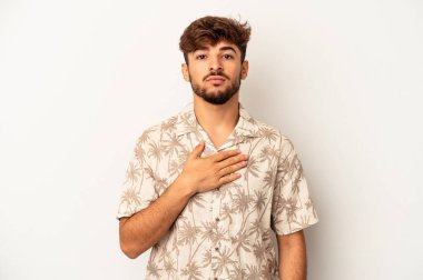 Genç melez adam gri arka planda izole edilmiş yemin ediyor, elini göğsüne koyuyor..