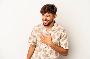 Gri arka planda yaşayan genç melez adam elini göğsünde tutarak kahkahalar atıyor..