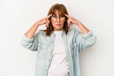 Beyaz arka planda izole edilmiş orta yaşlı beyaz kadın bir göreve odaklanmış, işaret parmaklarını işaret ediyor..