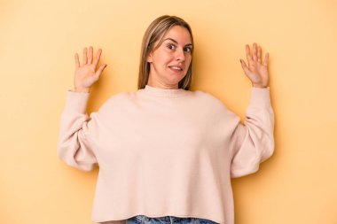 Sarı arka planda izole genç beyaz kadın yakın bir tehlike nedeniyle şoka uğruyor.