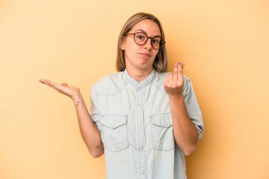 Sarı arka planda izole edilmiş genç beyaz kadın parasız olduğunu gösteriyor..