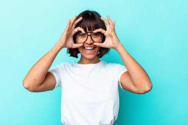 Mavi arka planda izole edilmiş genç melez kadın gözlerde sorun olmadığını gösteriyor.