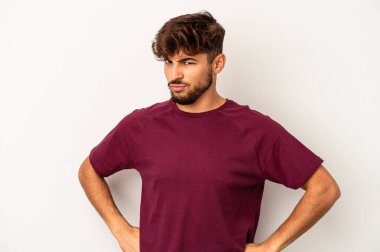 Genç melez adam, gri arka planda izole edilmiş hoşnutsuzca kaşlarını çatmış, kollarını kavuşturmuş..