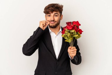 Genç melez adam elinde gül buketi tutuyor beyaz arka planda izole edilmiş parmakları dudaklarında bir sır saklıyor.