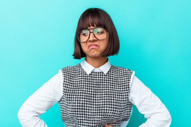 Mavi arka planda soyutlanmış genç melez kadın kafası karışmış, kuşkulu ve güvensiz hissediyor..