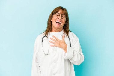 Middle age doctor woman isolated on pink background laughs out loudly keeping hand on chest.