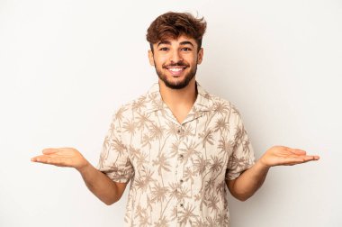 Gri arka planda soyutlanmış genç melez adam kollarıyla ölçeği yapıyor, mutlu ve kendinden emin hissediyor..