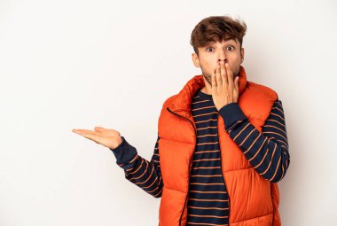 Genç melez adam gri arka planda izole edilmiş. Kopya alanını avuçlarında tutmaktan etkilenmiş..