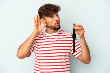 Mavi arka planda izole edilmiş bir kol saati tutan genç melez bir adam bir dedikoduyu dinlemeye çalışıyor..