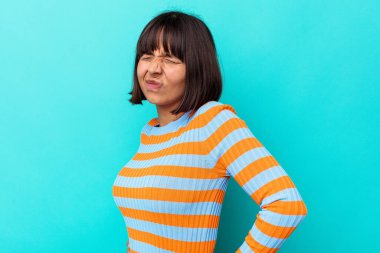 Genç melez kadın mavi arka planda izole edilmiş sırt ağrısı çekiyor..