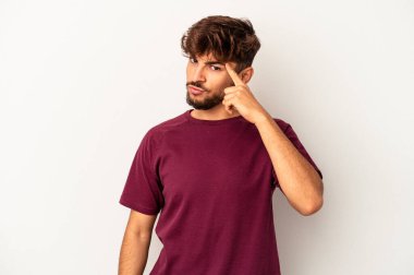 Genç melez adam gri arka planda izole edildi. Şakağı parmağıyla göstererek, düşünerek, bir göreve odaklandı..