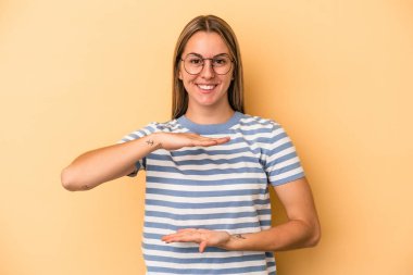 Sarı arka planda izole edilmiş beyaz bir kadın iki eliyle bir şey tutuyor..