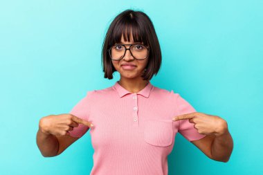 Mavi arka planda izole edilmiş genç bir ırk kadını gömlek fotokopisini elle gösteriyor, gururlu ve kendinden emin.