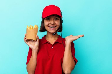 Genç melez ırk fast food restoranı çalışanı elinde kızartmalarla mavi arka planda bir fotokopi alanı ve belinde bir el daha olduğunu gösteriyor..