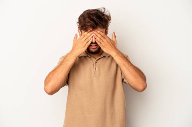 Genç melez adam, gri arka planda izole edilmiş elleri olan gözleri kapamaktan korkuyor..