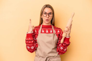 Genç fırıncı kadın, sarı arka planda izole edilmiş Noel için kurabiye yapıyor. Harika bir fikri var, yaratıcılık kavramı..