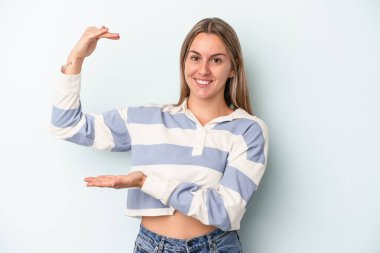 Kafkasyalı genç bir kadın mavi arka planda izole edilmiş. Elinde parmakları olan, gülümseyen ve kendinden emin bir şey var..