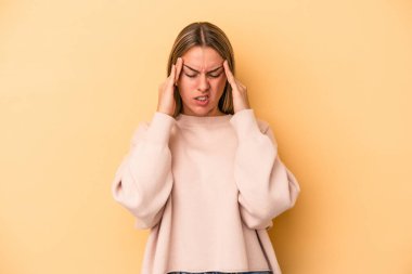 Sarı arka planda izole edilmiş, başı ağrıyan, yüzünün ön kısmına dokunan beyaz bir kadın..