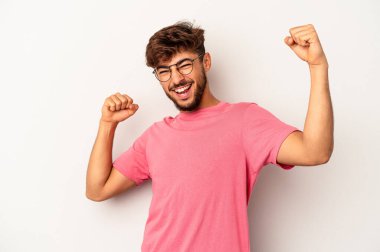 Genç melez adam gri arka planda izole edilmiş kaygısız ve heyecanlı tezahüratlar yapıyor. Zafer konsepti.