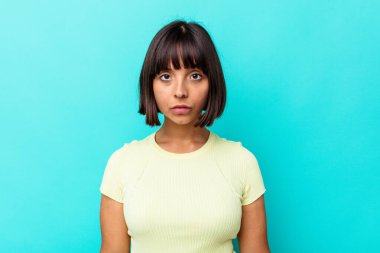 Genç melez kadın mavi arka planda izole edilmiş üzgün, ciddi yüzlü, mutsuz ve hoşnutsuz..