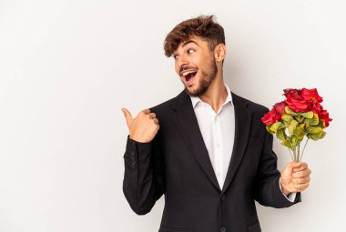 Genç melez adam elinde gül buketi tutuyordu. Beyaz arka planda izole edilmiş, baş parmak uzakta, gülen ve kaygısız..