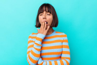 Mavi arka planda soyutlanmış genç melez bir kadın esniyor. Ağzıyla ağzını kapatan yorgun bir hareket sergiliyor..