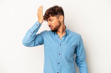 Genç melez adam gri arka planda izole edilmiş bir şekilde bir şeyi unutuyor. Alnına avuç içi ve kapalı gözlerle vuruyor..