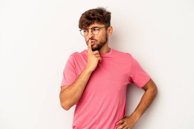 Genç melez adam gri arka planda izole edilmiş ya sır saklıyor ya da sessizlik istiyor..