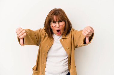 Beyaz arka planda izole edilmiş orta yaşlı beyaz kadın baş parmağını aşağı gösteriyor ve hoşlanmadığını ifade ediyor..