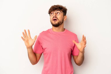 Genç melez adam gri arka planda izole edilmiş gökyüzüne haykırıyor, yukarı bakıyor ve hayal kırıklığına uğruyor..