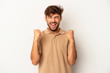 Genç melez adam gri arka planda izole edilmiş kaygısız ve heyecanlı tezahüratlar yapıyor. Zafer konsepti.