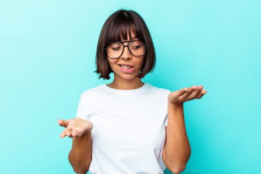 Mavi arka planda izole edilmiş genç bir ırk kadını elinde avuç içi bir şeyle kameraya sunuyor..