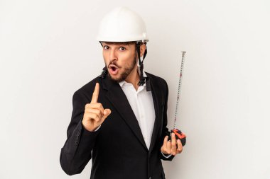 Miğfer takan ve taksimetre tutan genç mimar gri arka planda bir fikri, ilham verici bir konsepti var..