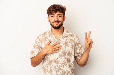 Genç melez adam gri arka planda izole edilmiş yemin ediyor, elini göğsüne koyuyor..