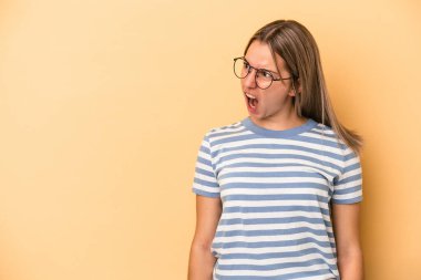 Sarı arka planda izole edilmiş genç beyaz kadın çok kızgın, öfkeli, hayal kırıklığına uğramış.