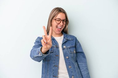 Mavi arka planda izole edilmiş genç beyaz kadın iki numarayı parmaklarıyla gösteriyor..