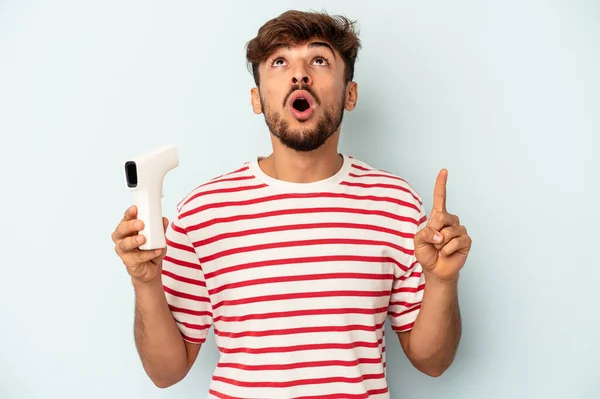 Ung Blandras Man Håller Termometer Isolerad Blå Bakgrund Pekar Upp — Stockfoto