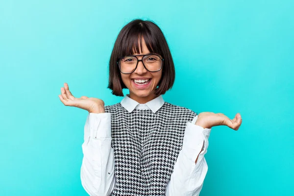 Mavi arka planda izole edilmiş genç melez kadın hoş bir yüz ifadesi sergiliyor..