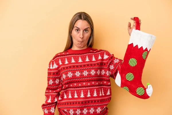 Young Caucasian Woman Holding Elf Sock Isolated Yellow Background Shrugs — Stock Photo, Image