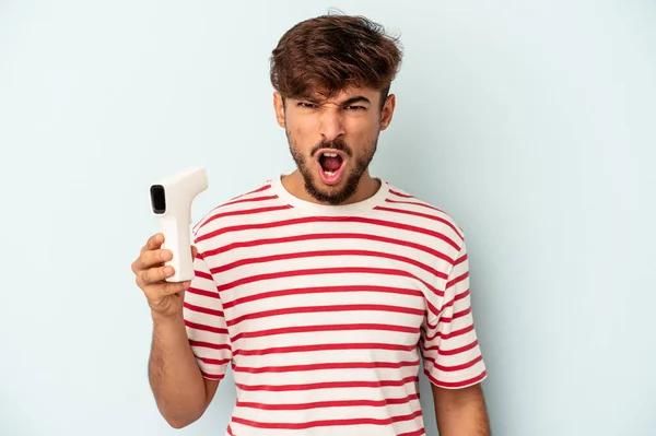 Young Mixed Race Man Holding Thermometer Isolated Blue Background Screaming — Fotografia de Stock