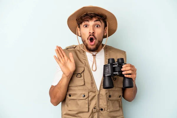 Young Mixed Race Man Holding Binoculars Isolated Blue Background Surprised — 图库照片