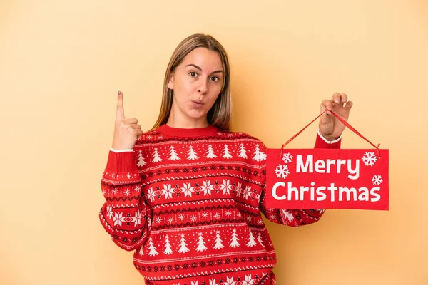 Mladá Běloška Drží Veselé Vánoční Plakát Izolované Žlutém Pozadí Nějakou — Stock fotografie