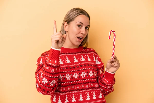 Sarı Arka Planda Izole Edilmiş Bir Noel Çubuğu Tutan Beyaz — Stok fotoğraf