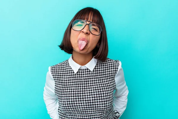 Mavi arka planda soyutlanmış genç melez bir kadın. Komik ve dost canlısı bir dil uzatıyor..