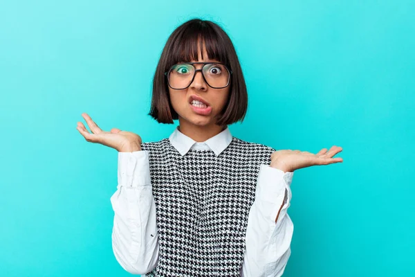 Genç melez kadın, mavi arka planda izole edilmiş şüpheli ve sorgulama sırasında omuz silkiyor..