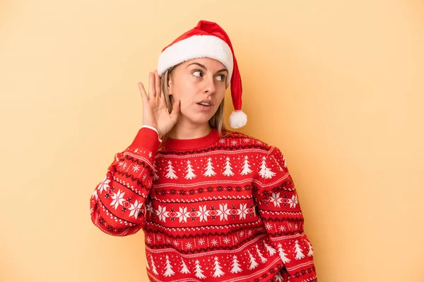 Νεαρή Λευκή Γυναίκα Γιορτάζει Χριστούγεννα Απομονωμένη Κίτρινο Φόντο Προσπαθώντας Ακούσει — Φωτογραφία Αρχείου