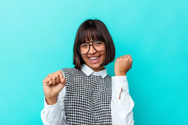 Genç melez kadın mavi arka planda izole edilmiş dans ediyor ve eğleniyor..