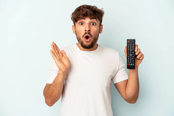 Jovem Mestiço Segurando Controlador Isolado Fundo Azul Surpreso Chocado — Fotografia de Stock