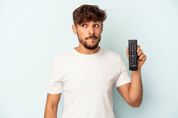 Jovem Mestiço Segurando Controlador Isolado Fundo Azul Confuso Sente Duvidoso — Fotografia de Stock